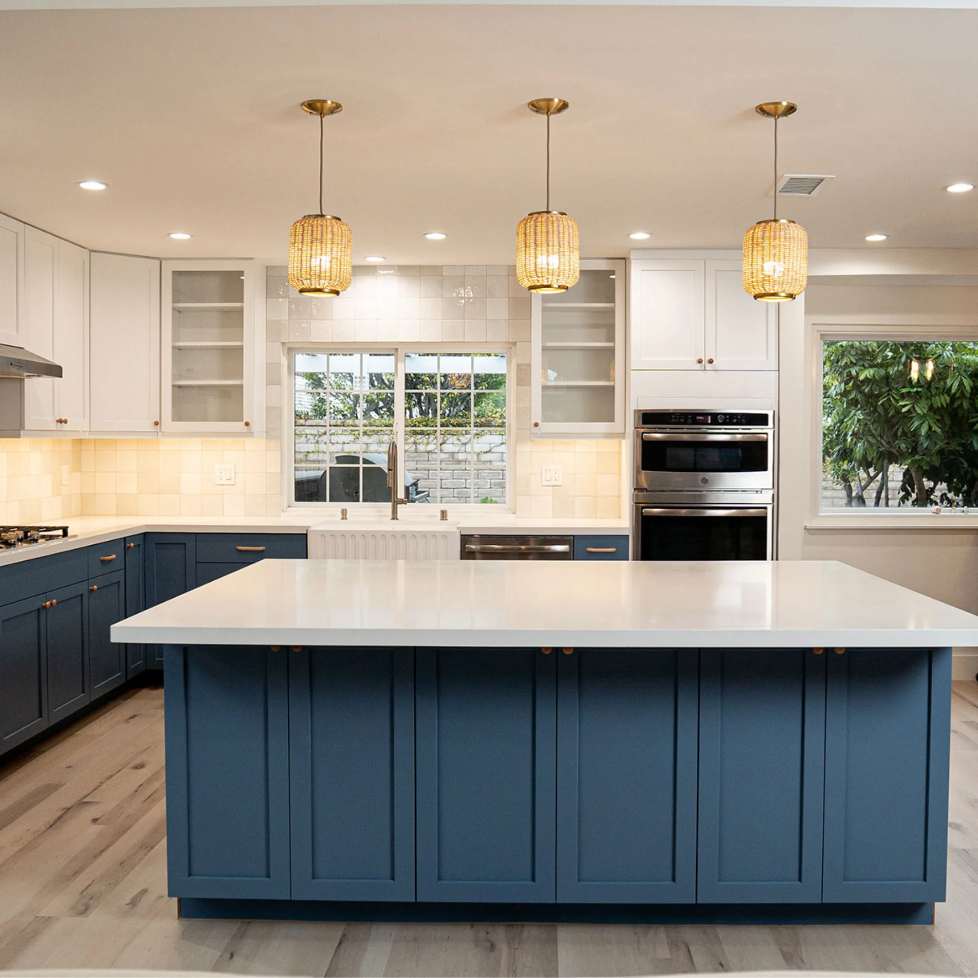 Bright kitchen with a navy island and warm pendant lights, shown as design inspiration